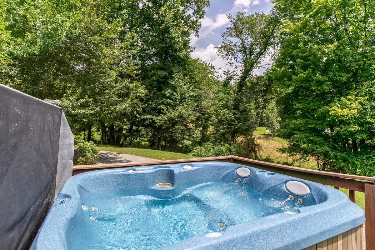 The image displays a wooden deck with a bubbling hot tub set against a backdrop of lush greenery, inviting moments of relaxation and socializing after a day of exploration. The tranquil ambiance reflects the peacefulness of the lake and mountain environment.